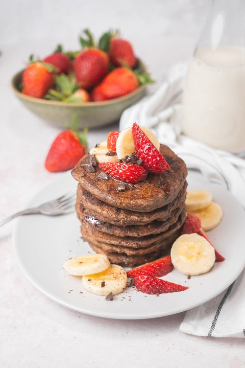 Serveersuggestie: stapel pannenkoeken met banaan, bessen en siroop